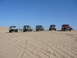 1988 Ford Bronco - A convoy of modified SUVs traverses a sandy desert landscape.