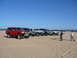 1988 Ford Bronco - A group of Ford Broncos and other SUVs are lined up on a sandy landscape under a clear blue sky.