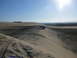 1988 Ford Bronco - A dark SUV navigates a sandy incline under a bright, sunny sky, leaving tire tracks in its wake.