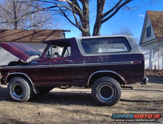 Maroon Ford Bronco with hood up, side view. Looks like a 70s model