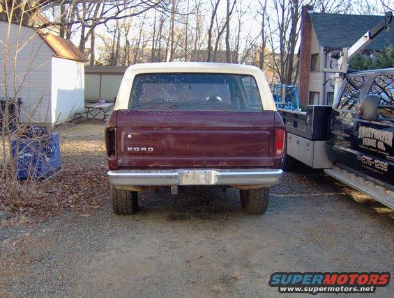 Rear view of maroon Ford Bronco with white top. Text on adjacent truck reads 'SWEETWATER FENCE CO.'