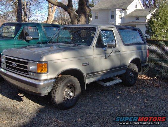 Gray Ford Bronco parked next to a green Ford Bronco. A sign on the gray Bronco's window says "A/C Auto Repair"