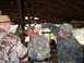 1995 Ford Bronco - Three men in camouflage are gathered inside a barn, with one man appearing to have blood on his face.