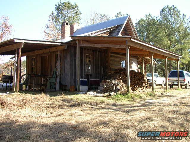Log cabin with a white pickup truck and a dark SUV parked in front