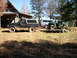 1995 Ford Bronco - A 1995 Ford Bronco is parked in a grassy area next to a log cabin, with a utility vehicle on a trailer behind it.