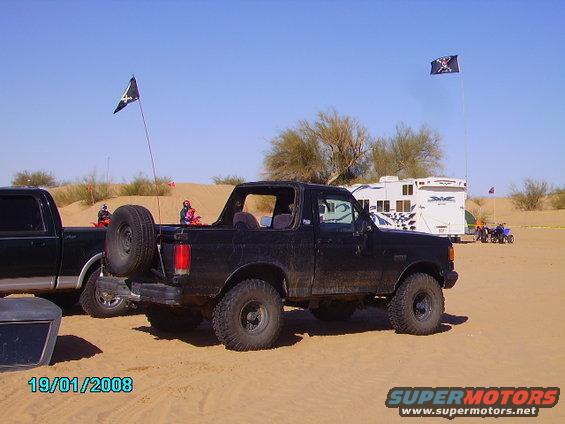 Black 1990 Ford Bronco with spare tire on rear, parked in sand dunes