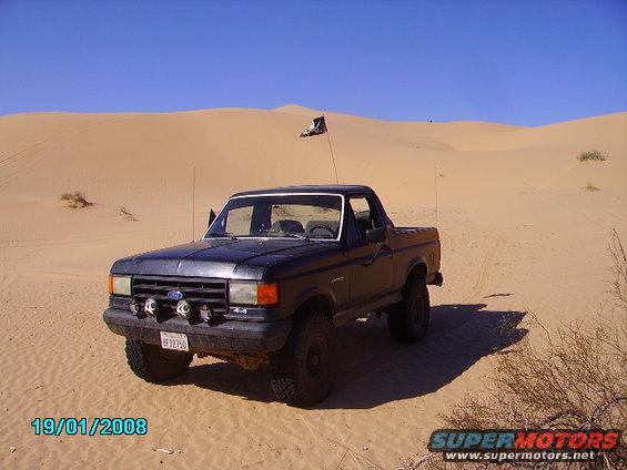 Ford F-150 pickup truck in sand dunes, flag on antenna