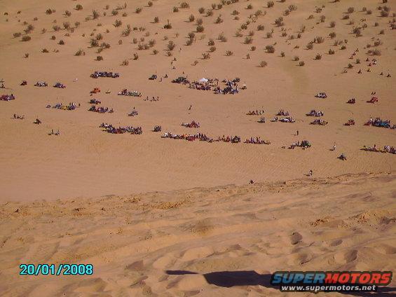 People gathered in a desert with many ATVs and off-road vehicles