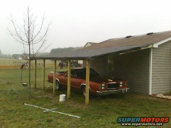 1979 Ford Ranchero parked under a wooden carport next to a house