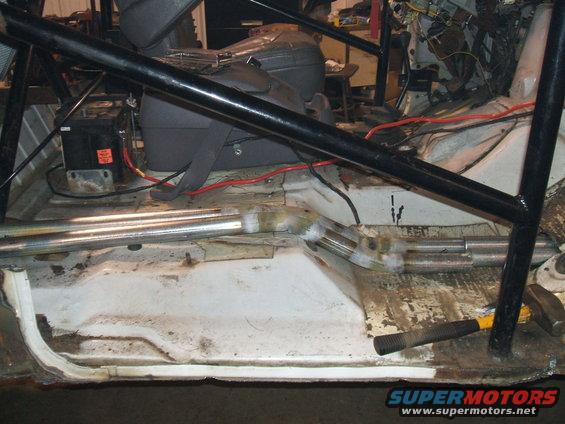 Vehicle interior showing floor pan, battery, and part of a roll cage