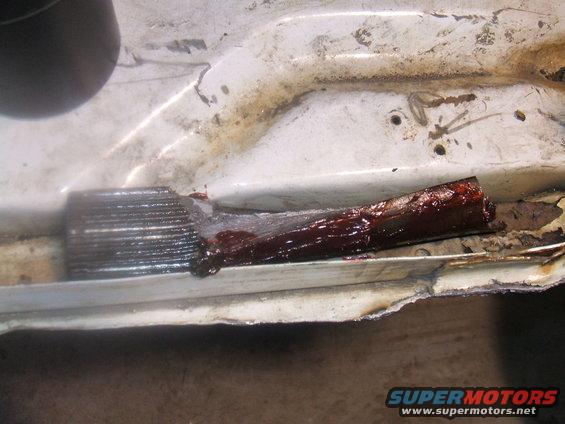 close-up of rusted metal with dark grease and some red fluid