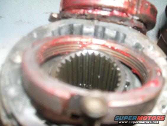 Close-up of a greasy differential gear assembly with red grease on the threads