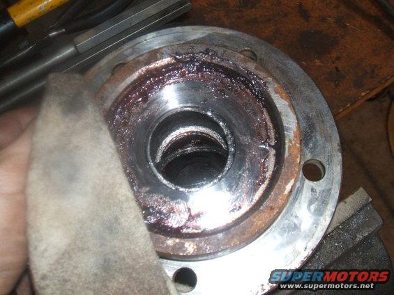 Close-up of a greasy, rusty wheel bearing assembly with a rag nearby