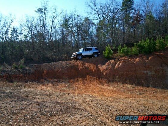 Silver SUV on a dirt hill with trees in the background