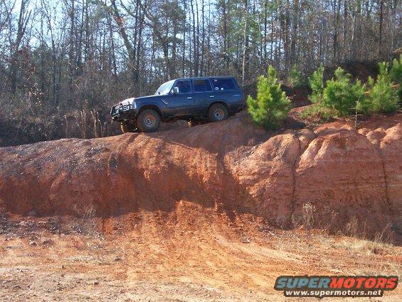Dark blue SUV with a brush guard on a dirt hill, tires are muddy