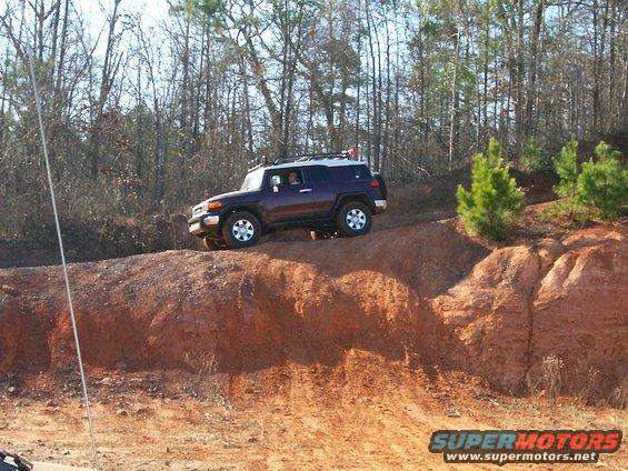 Dark purple SUV on dirt hill, Supermotors logo visible