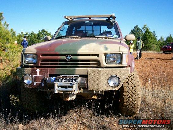 Camouflaged pickup truck front view with diamond plate bumper and winch