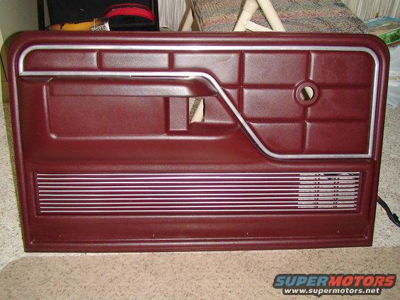 Maroon car door panel with silver trim and horizontal speaker grille