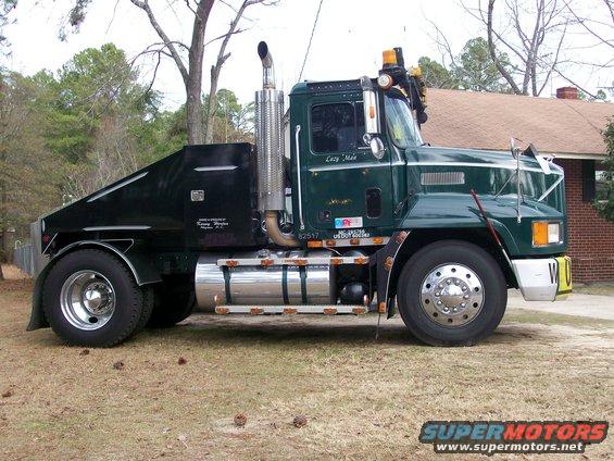Green semi-truck with a custom black rear body and large chrome exhaust stack. Text on door reads 'Lazy Main'