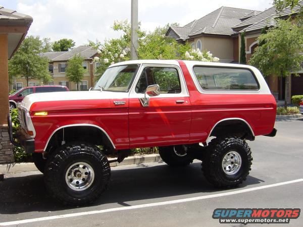 1978 Ford Bronco, red and white, lifted with large tires, parked outdoors