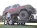 1978 Ford Bronco - A woman stands beside a heavily mud-covered 1978 Ford Bronco loaded onto a trailer.