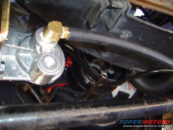 Transmission fluid cooler with brass fittings and black hoses, part of a vehicle's undercarriage