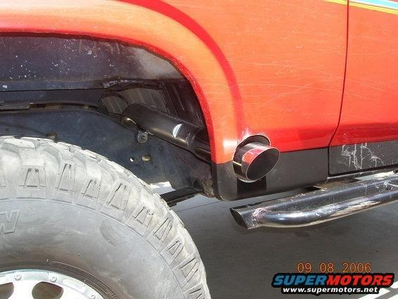 Close-up of a red vehicle's rear tire and exhaust pipe exiting the body