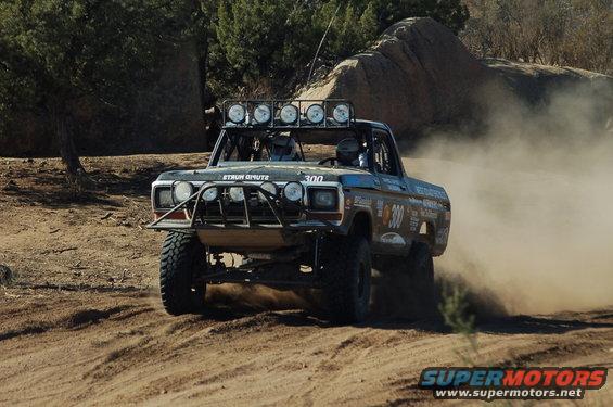 Off-road race truck kicking up dust, front view. Modified 1970s Ford F-Series truck