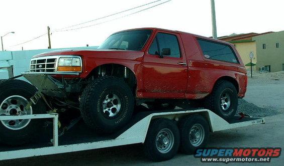 red Ford Bronco on a trailer, lifted with large tires