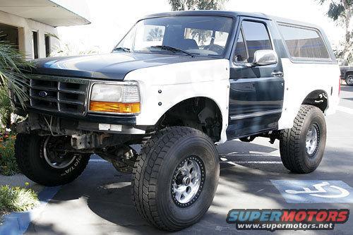 Ford Bronco with a two-tone paint job, lifted suspension, and off-road tires parked in a lot
