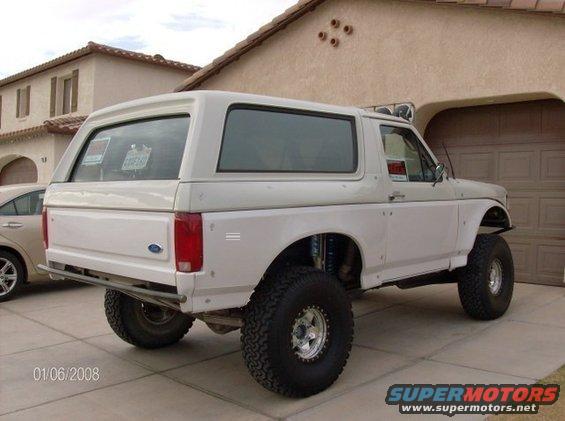White 1986 Ford Bronco with large off-road tires parked in a driveway