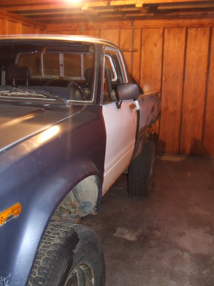 Pickup truck with mismatched body panels, dark blue and white, in a garage