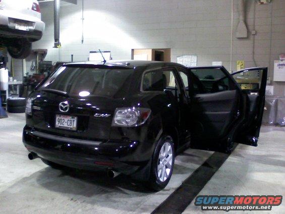 black 2007 Mazda CX-7 parked inside a garage with doors open