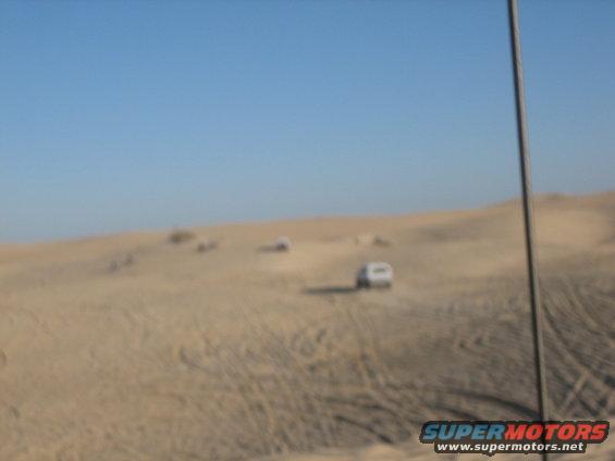 White 1995 Ford Bronco driving on sand dunes