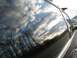 2002 Volkswagen Passat - The side window of a vehicle reflects a cloudy sky and bare trees.