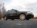 2002 Volkswagen Passat - This black wagon, seen from a 3/4 front angle, features a roof rack and aftermarket wheels.