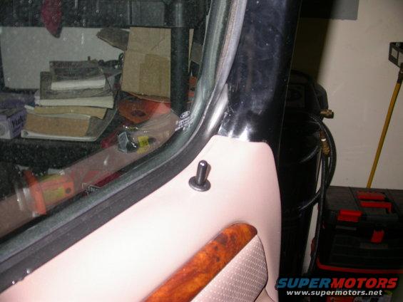 Door panel with wood trim and a black push pin, next to a black window frame