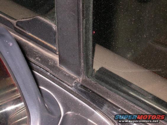 Close-up of a vehicle's door frame and window seal, showing rubber trim and metal components