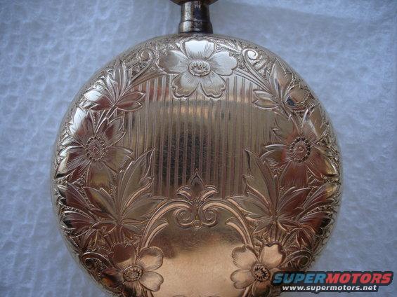 Gold pocket watch with intricate floral engravings and vertical lines