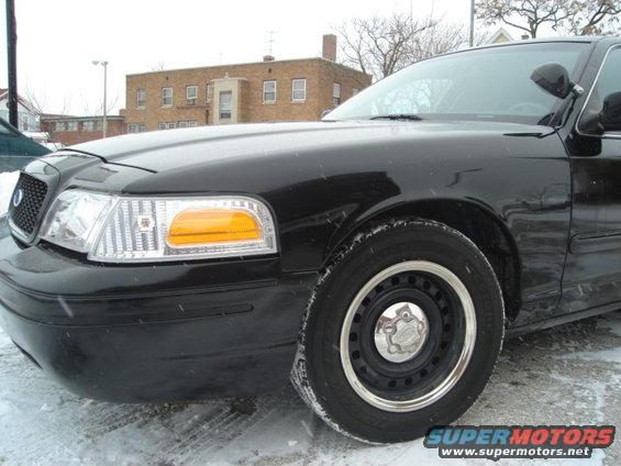 Front corner of black sedan, possibly a 2000 Ford Crown Victoria, parked on a snowy street
