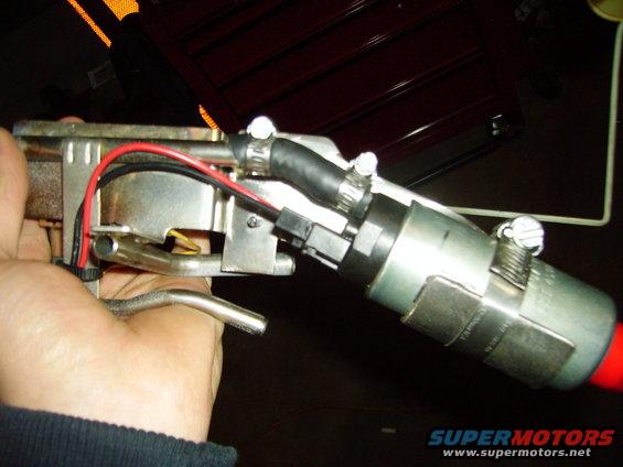 Fuel pump assembly with red and black wires, held by a hand. A black hose is attached