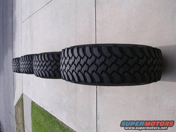 Four black off-road tires lined up on concrete