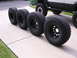 1983 Ferrari Enzo - A set of four large off-road tires are displayed on a driveway next to a lifted vehicle.