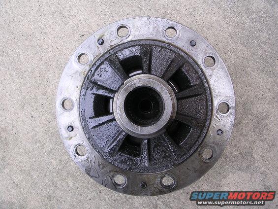 Differential carrier with a silver flange and black gears, resting on a concrete surface