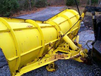 Yellow snow plow attached to a dark vehicle, viewed from the side