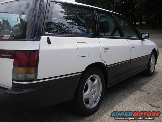 1994 Subaru Legacy wagon, side view. White upper body with black lower trim and bumper