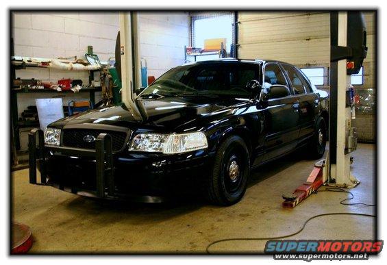 Black 2003 Ford Crown Victoria with a push bar on a car lift in a garage