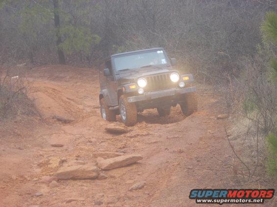 Jeep Wrangler driving on a muddy, rocky trail