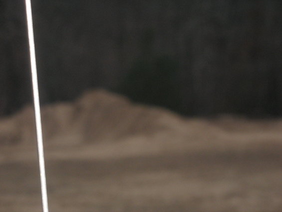 Dirt pile and dark trees in the background, with a vertical white line on the left