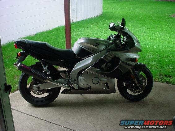Silver Yamaha FZR600 motorcycle parked on concrete, side view, black seat and exhaust